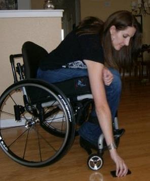 Woman in wheelchair picking up a phone from off the floor