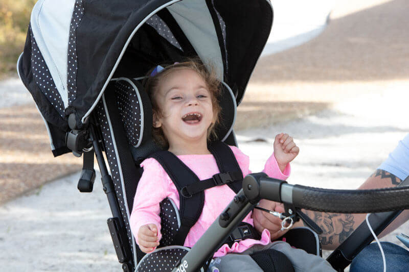 A smiling child in an early intervention adaptive stroller